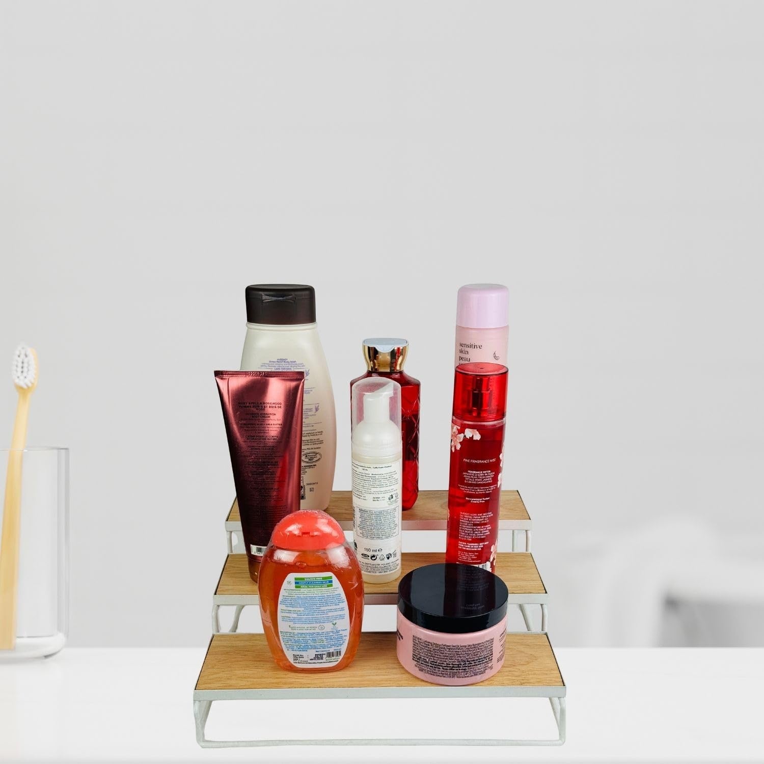GoHooked white 3-tier wooden shelf organizer displaying various toiletries and cosmetics. Includes a toothbrush in a glass.