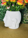 GoHooked white plastic Buddha head shaped flower pot with textured hair, holding colorful flowers.