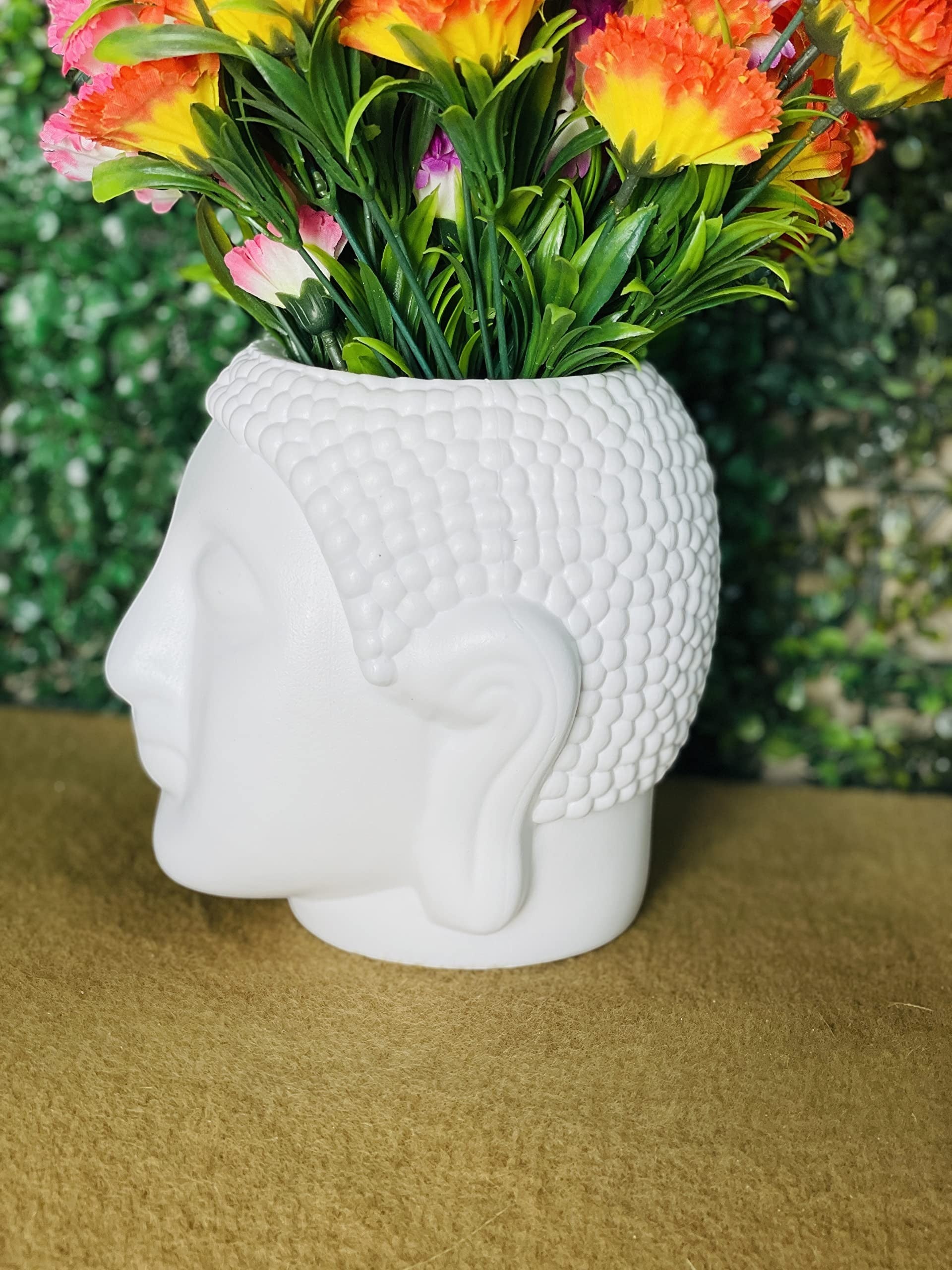 GoHooked white Buddha head shaped plastic planter pot with textured hair detail, holding colorful artificial flowers.