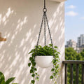 Go Hooked Henri 7-inch round white textured polymer hanging planter pot with black metal chain, filled with green trailing plants.