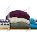 Go Hooked white coated iron shelf dividers organizing stacked sweaters and towels on a wooden shelf.