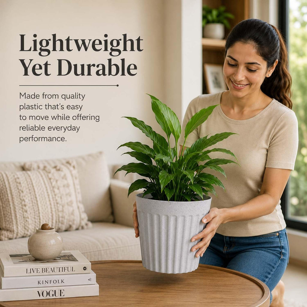 A woman holding a GoHooked white marble-textured ribbed plastic planter pot with a lush green plant in a living room.