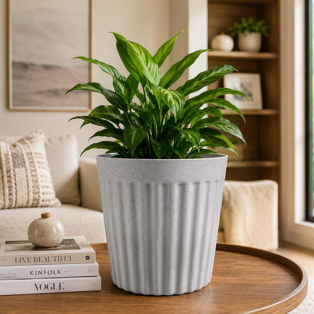 GoHooked white marble texture ribbed plastic planter pot holding a lush green plant on a wooden table in a living room