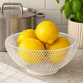 Go Hooked white double-layer metal mesh fruit bowl with lemons on a kitchen counter.