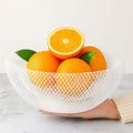 Go Hooked white double-layer metal mesh fruit bowl filled with oranges and green leaves. 12-inch basket.