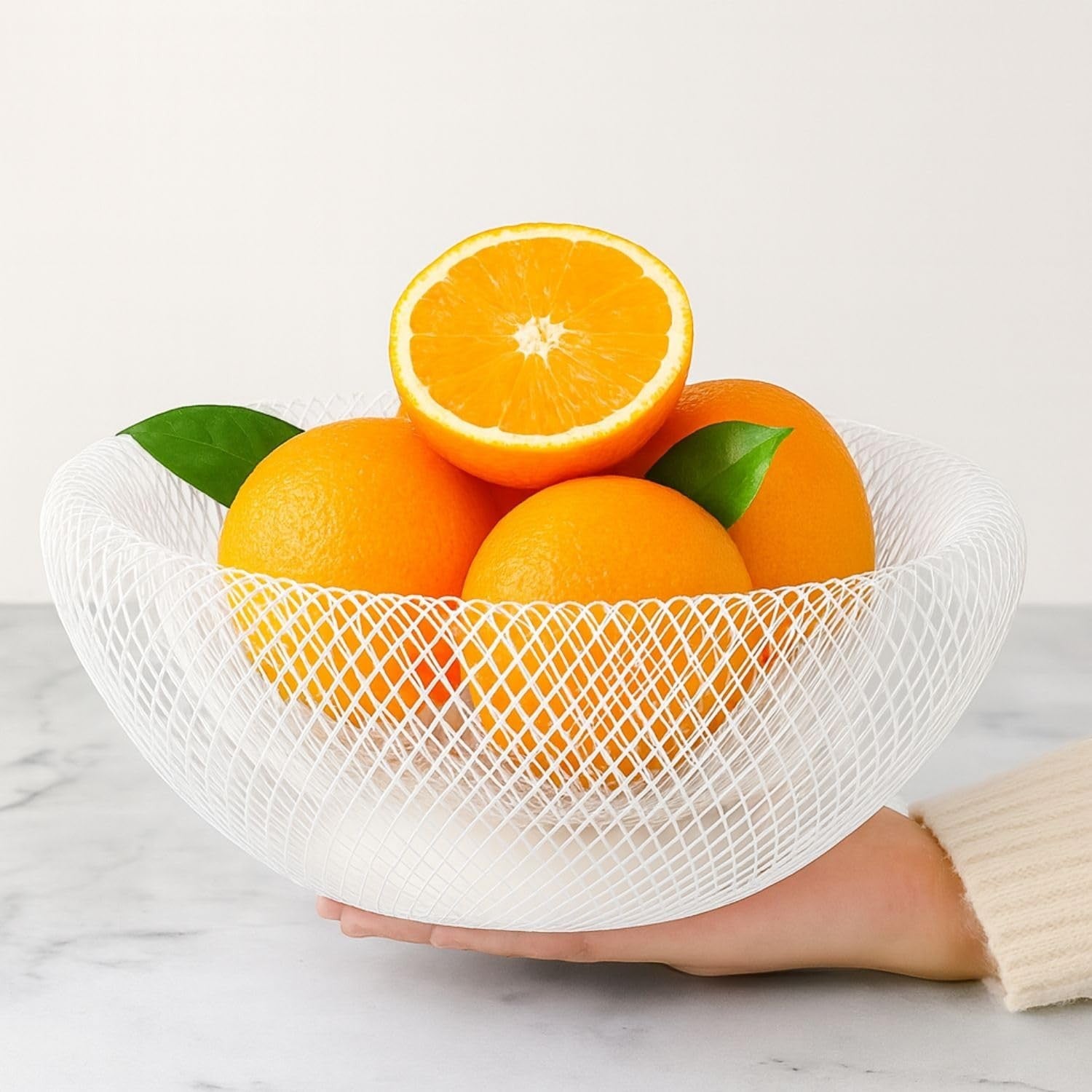 GoHooked white metal mesh fruit bowl filled with oranges and leaves. Modern, airy design.