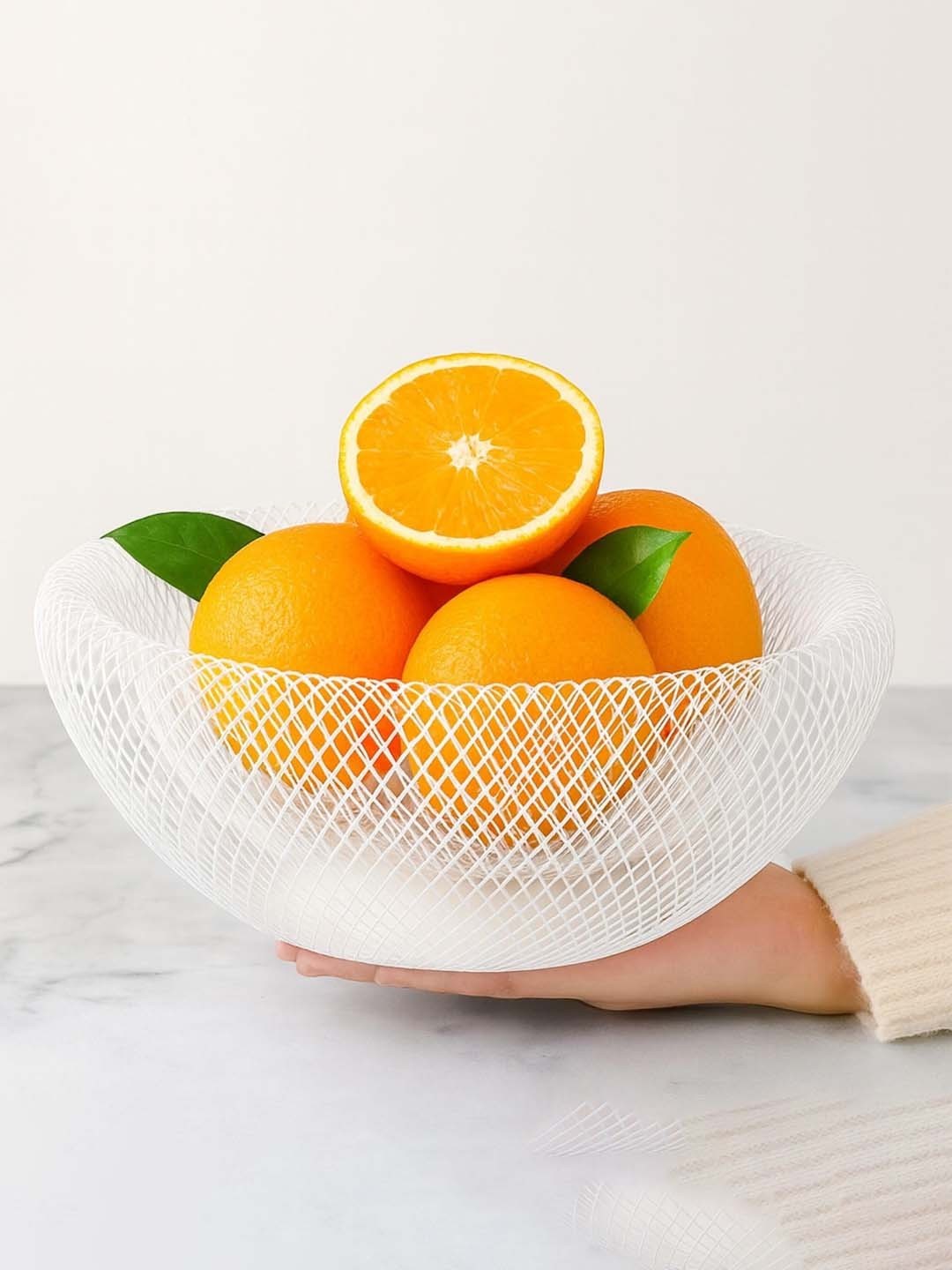 GoHooked white metal mesh fruit bowl holding fresh oranges on a marble surface