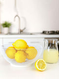 GoHooked white metal mesh fruit bowl filled with fresh yellow lemons on a kitchen countertop
