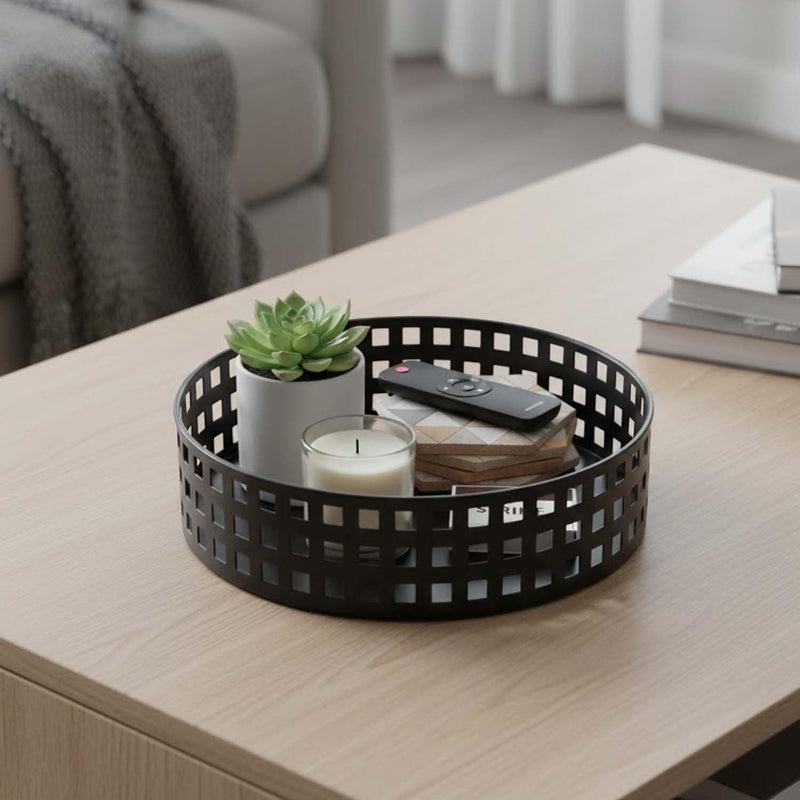 Go Hooked white metal revolving fruit basket with a grid pattern, holding a plant, candle, and remote.