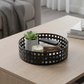 Go Hooked white metal revolving fruit basket with a grid pattern, holding a succulent plant, candle, and remote.