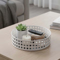Go Hooked white metal revolving organizer tray with a grid pattern, holding a plant, candle, remote, and coasters.