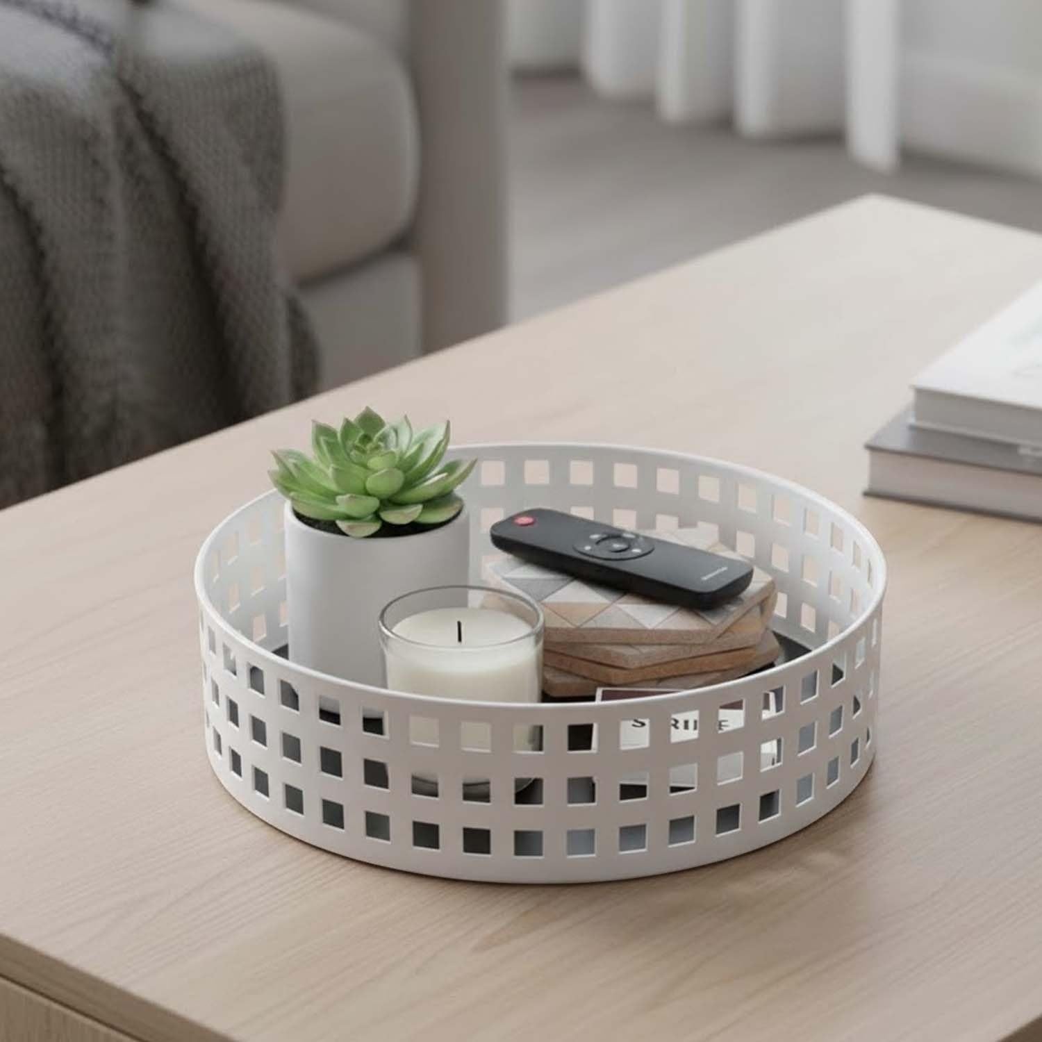 GoHooked white metal revolving organizer tray with a grid pattern, holding a succulent plant, candle, remote, and coasters on a coffee table.