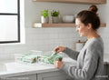 GoHooked white metal wire grid storage basket bin with handles, used to organize packets on a kitchen counter.