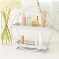 Go Hooked white metal 2-tier vanity storage organizer with circular frame, holding makeup and toiletries.