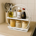 GoHooked white 2-tier metal vanity storage organizer with bamboo-lidded jars and bottles on countertop.