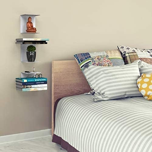 GoHooked white heavy duty iron wall mounted shelves displaying books, a plant, and decor in a bedroom.