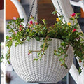 GoHooked white plastic hanging pot with woven texture, holding blooming plants with pink and yellow flowers.
