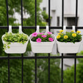 GoHooked white plastic railing hanging planter pots with pink and yellow flowers on a black fence.