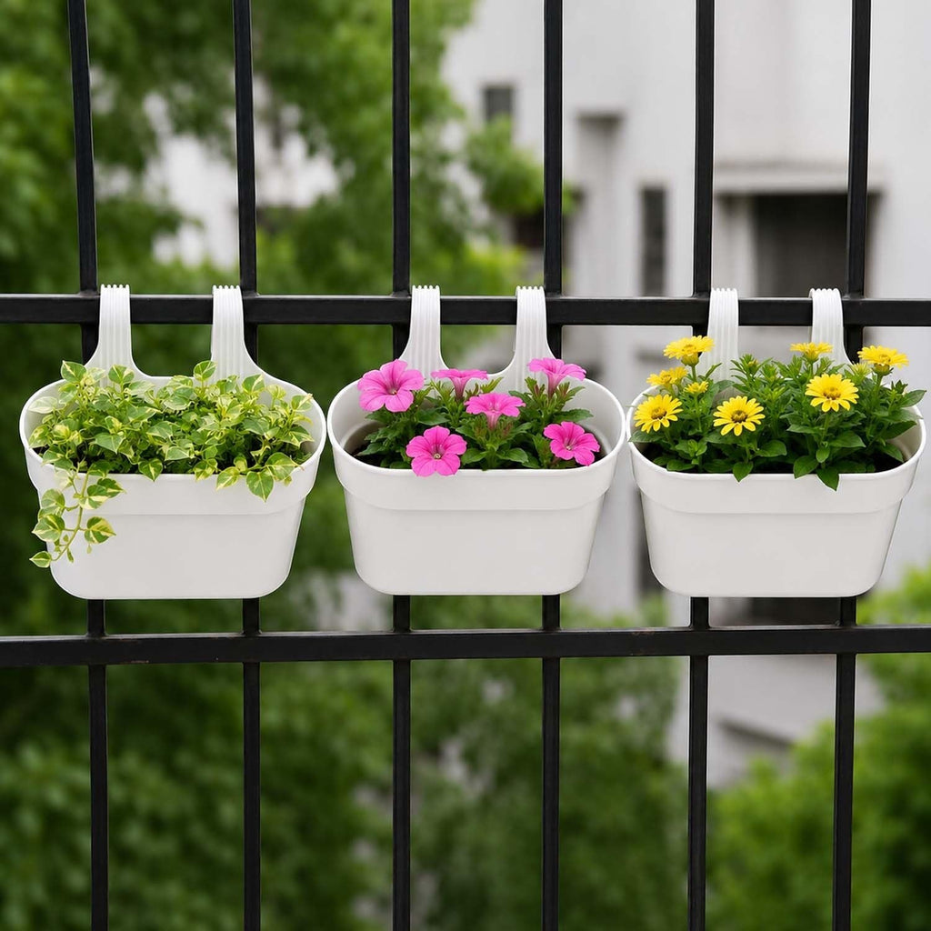 GoHooked white plastic railing planters with pink and yellow flowers, set of 3 shown hanging on a black fence.