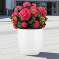 Go Hooked 24-inch white polymer round planter with drainage hole, holding pink hydrangeas.
