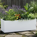 GoHooked white rectangular polymer planter pot filled with lush green plants and small yellow and orange flowers, set outdoors on stone pavers.