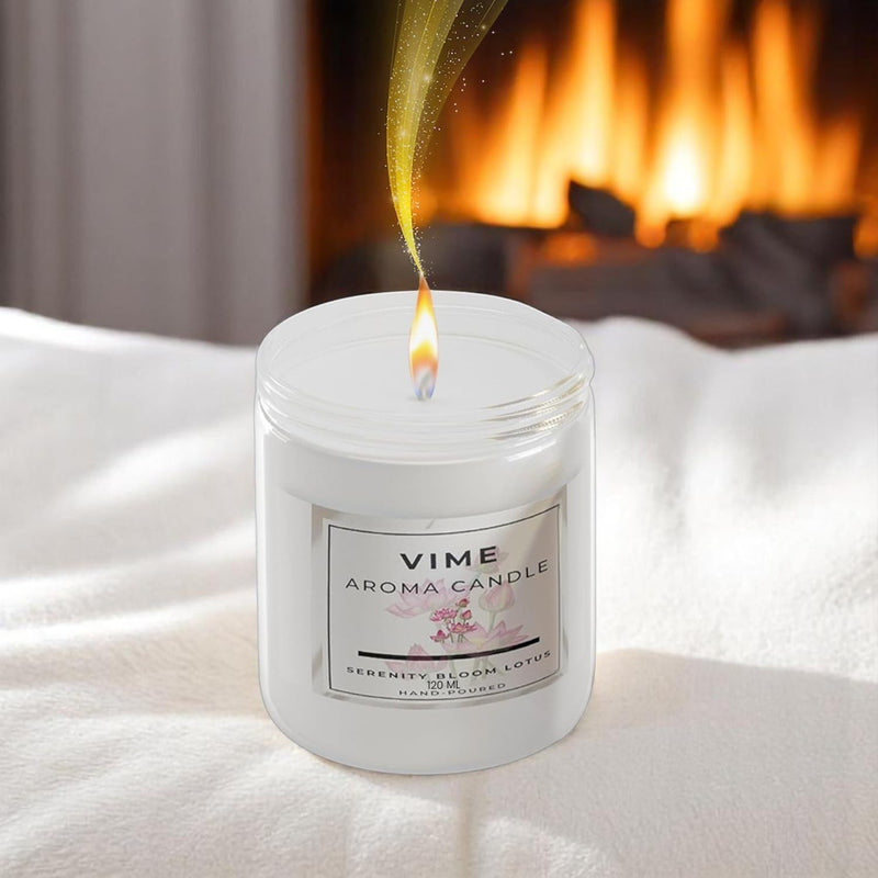 GoHooked white glass jar candle with Serenity Bloom Lotus fragrance, lit flame, cozy fireplace background.