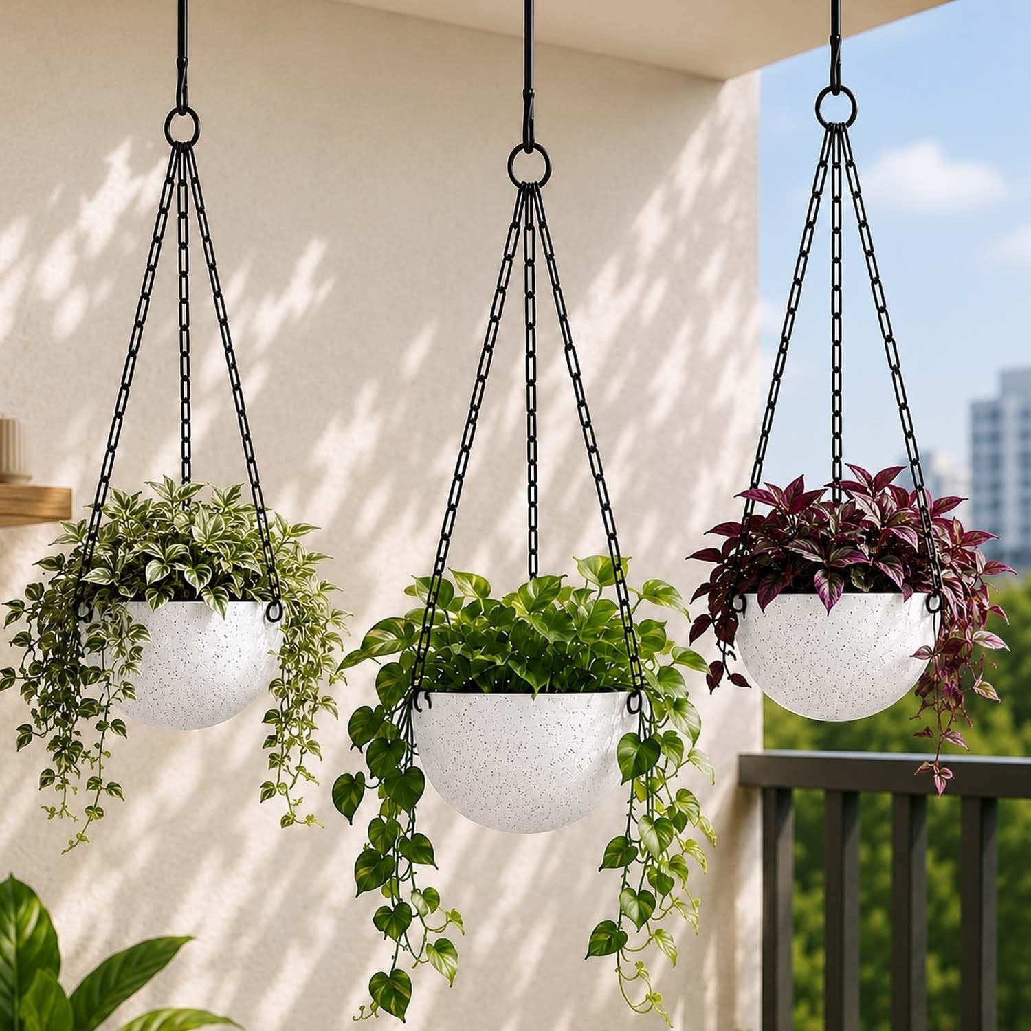 GoHooked set of 3 white speckled round hanging planters with black chains, filled with lush green plants.