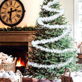 GoHooked snow white tinsel garland draped around a decorated Christmas tree. Festive holiday decor.
