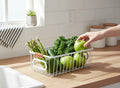 GoHooked white wire grid storage basket bin filled with fresh produce like apples, kale, asparagus, and cucumber on a kitchen counter.