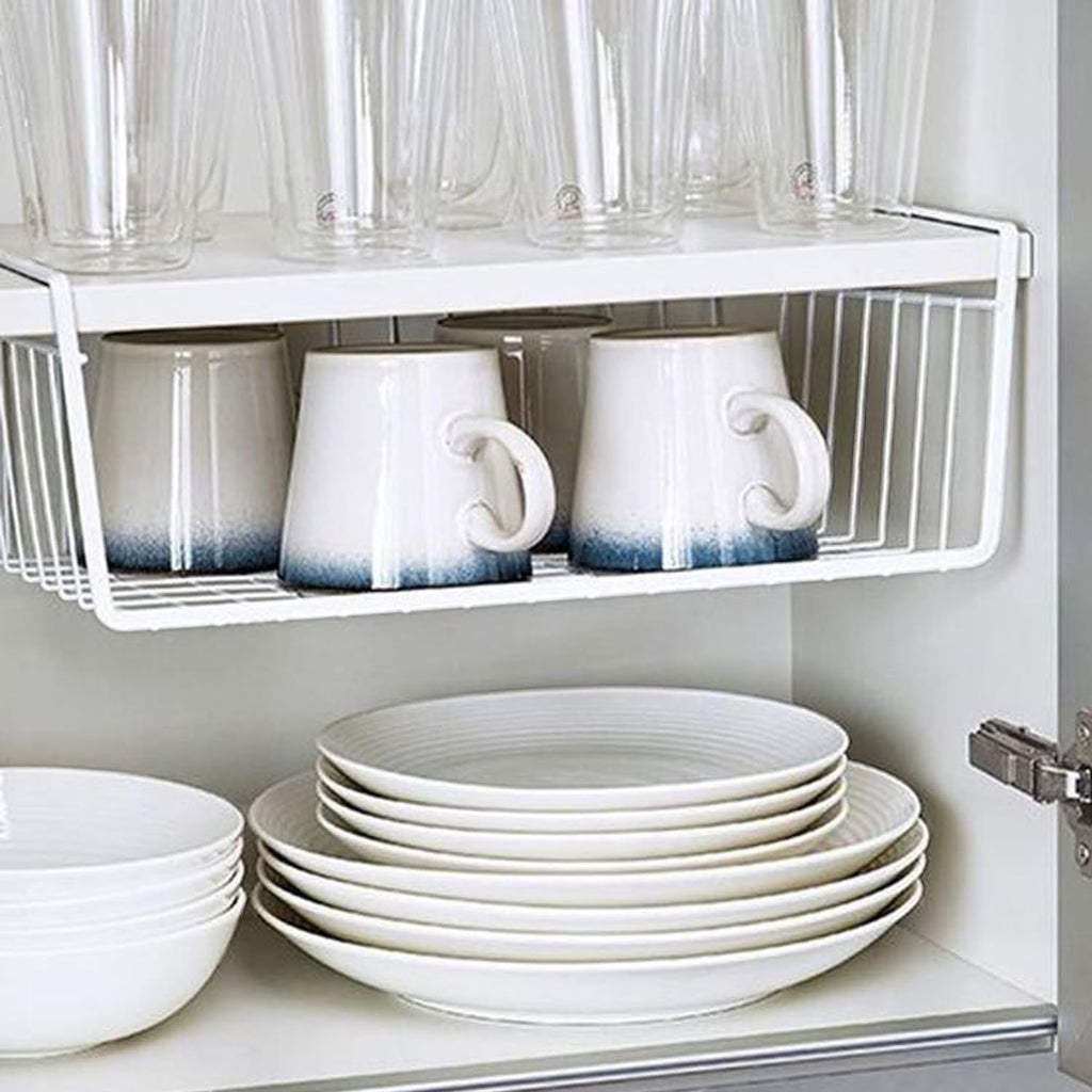 GoHooked white wire undershelf storage basket holding mugs, with glasses on shelf above and plates below.