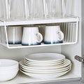 GoHooked white wire undershelf storage basket holding mugs, with glasses on shelf above and plates below.