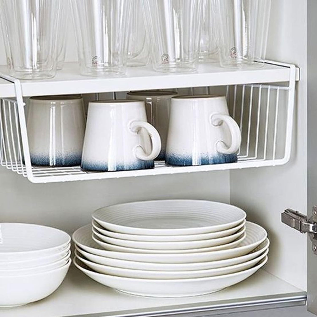 GoHooked white wire undershelf storage basket holding mugs, with glasses above and plates below.