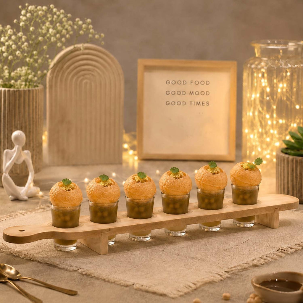 GoHooked wooden serving paddle with six clear shot glasses filled with pani puri, set on a rustic table for entertaining.