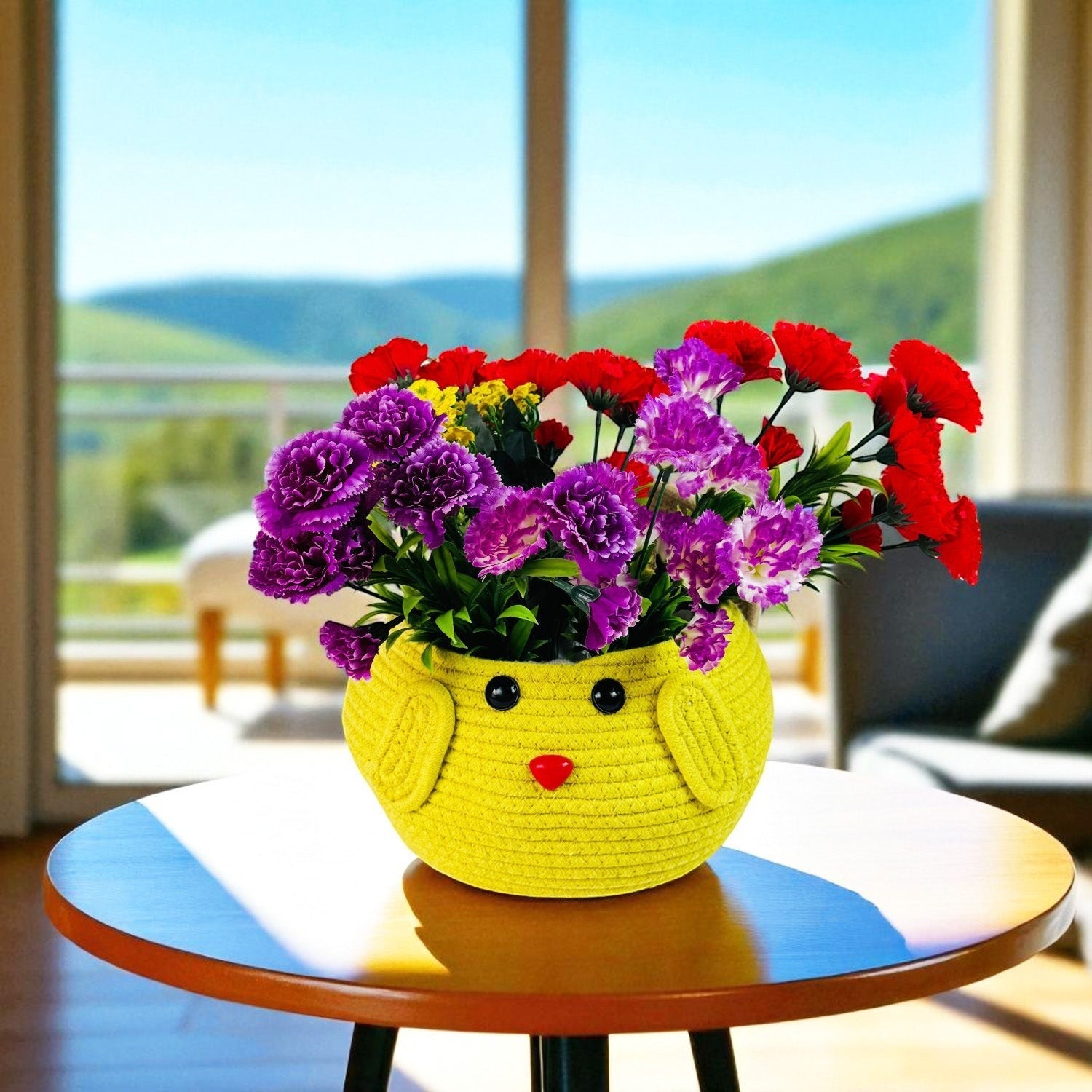 GoHooked yellow cotton rope storage basket with a cute face design, filled with colorful flowers on a wooden table.