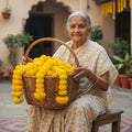 Go Hooked yellow marigold artificial flower garlands in a basket held by an elderly woman.