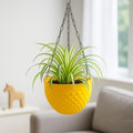 GoHooked yellow plastic hanging planter with woven texture and metal chain, holding a spider plant.