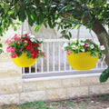 GoHooked yellow plastic hanging planter with woven texture, holding pink and red flowers.