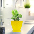 Go Hooked yellow plastic planter pot with saucer, featuring a diamond-patterned exterior and a healthy green plant.