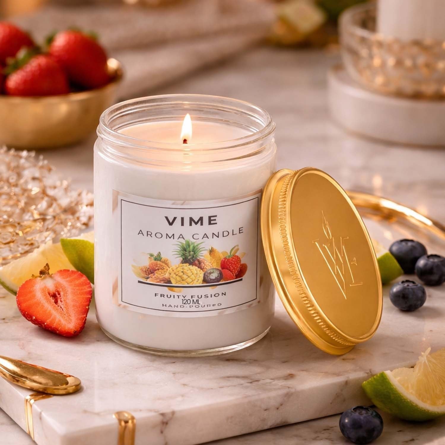 ViMe white glass jar candle with a golden lid, featuring a "Fruity Fusion" label and surrounded by fresh strawberries, blueberries, and lime slices.